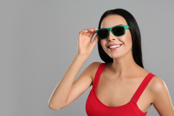 Naklejka premium Beautiful woman wearing sunglasses on grey background