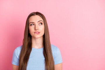 Photo portrait of cunning girl biting lip looking at blank space isolated on pastel pink colored...