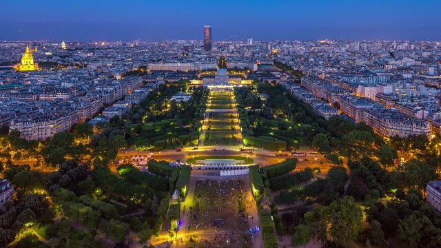 Aerial view of a large city skyline with Field of Mars and park after sunset day to night transition timelapse. Top view from the Eiffel tower observation deck. Paris, France.