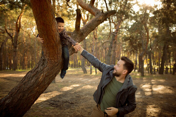 Playful. Father and son walking and having fun in autumn forest, look happy and sincere. Laughting, playing, having good time together. Concept of family, happiness, holidays, childhood, lifestyle.