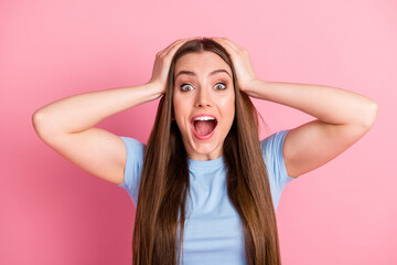 Photo portrait of excited screaming woman holding head with two hands isolated on pastel pink colored background