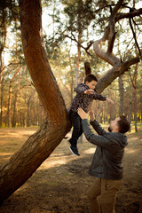 Playful. Father and son walking and having fun in autumn forest, look happy and sincere. Laughting, playing, having good time together. Concept of family, happiness, holidays, childhood, lifestyle.