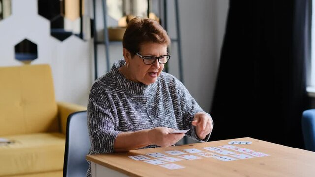 senior woman playing solitaire at home. Happy old lady plays an intellectual game close up Shot video.