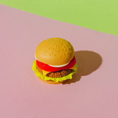 Appetizing burger with shadow on green and pink background. Creative concept. Plastic pop art...