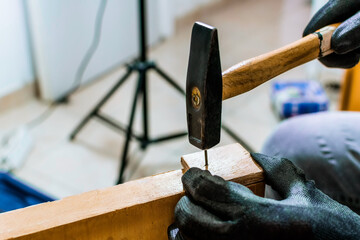Closeup of hammering in nails. Man doing carpentry work at home, assembling furniture, practicing craft hobby.