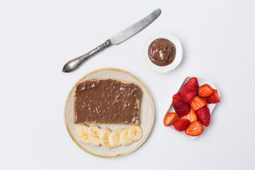 Bread covered by chocolate paste and strawberry and banana