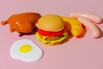 Dinner party meal ingredients like burger, chicken or turkey, sausages, fried egg and croissant on pink background. Creative plastic isometric concept. Minimalism