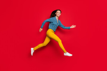 Full length body size profile side view of pretty cheerful thin motivated girl jumping running isolated on bright red color background