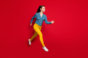 Full length body size view of attractive fit cheerful girl jumping running fast isolated over bright red color background