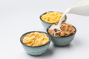 Corn and wholegrain flakes in bowl on white background