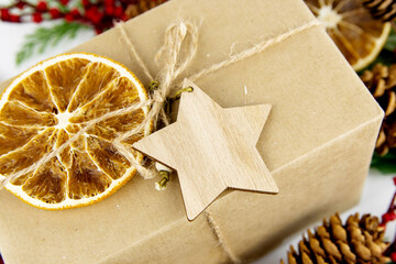 Close-up of craft gift box with wooden star and dried orange. Eco-friendly packaging concept for Christmas.