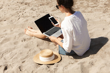 Young woman using laptop computer on a beach. Vacation lifestyle communication. Freelance work...