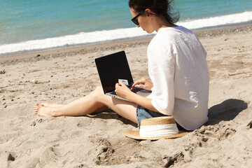 Young woman using laptop computer on a beach. Vacation lifestyle communication. Holds a Bank card in his hands. The concept of online shopping or online shopping