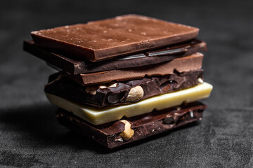 Stack of chocolate slices with mint leaf on a wooden table.Assortment of fine chocolates in white, dark, and milk chocolate. Sweet food photo concept.