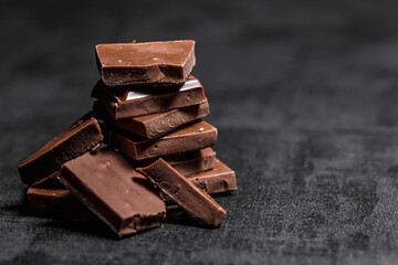 Stack of chocolate slices with mint leaf on a wooden table.Assortment of fine chocolates in white, dark, and milk chocolate. Sweet food photo concept.