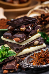 Stack of chocolate slices with mint leaf on a wooden table.Assortment of fine chocolates in white, dark, and milk chocolate. Sweet food photo concept.