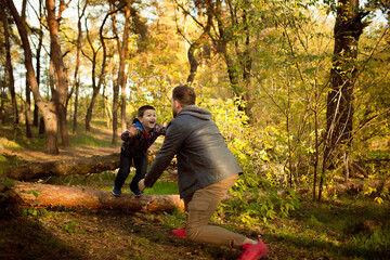 Warm. Father and son walking and having fun in autumn forest, look happy and sincere. Laughting, playing, having good time together. Concept of family, happiness, holidays, childhood, lifestyle.