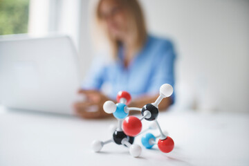 beautiful blond young woman with blue shirt with molecular model in modern office