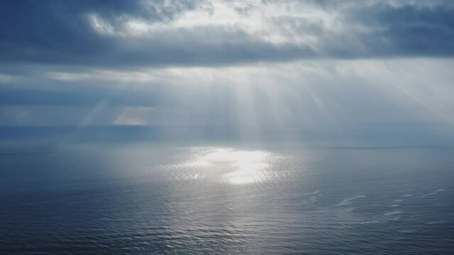 Sunrise over the sea. Sun Rays illuminating the sea thru the clouds. Aerial view. Calm at sea water. Clear overcast background