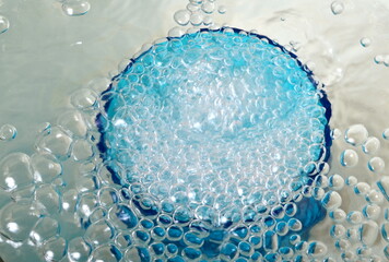 Overflowing water in a blue glass, full overflow glass with water and bubbles