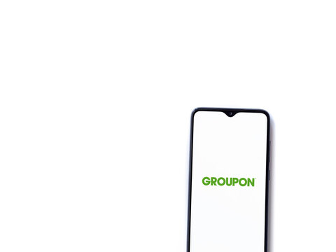 Lod, Israel - July 8, 2020: Groupon app launch screen with logo on the display of a black mobile smartphone isolated on white background. Top view flat lay with copy space.