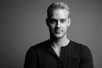 Young handsome man with blond hair against gray background