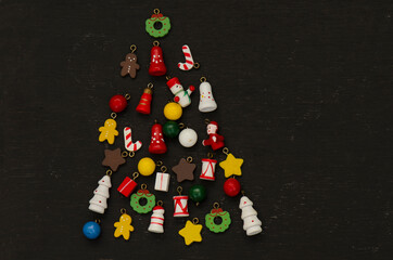 Top view of mini wood Christmas ornaments decoration arrange in Christmas tree shape on black wood table top background