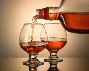 Cognac is poured from a bottle into a glass, close-up