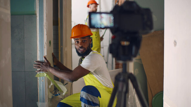 Portrait of african renovation worker filming video about wall construction on camera
