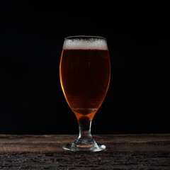 glass of beer on a wooden table with dark background
