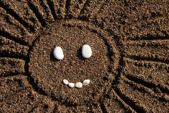 Sun on the sand. The smiley face is funny. Summer background.