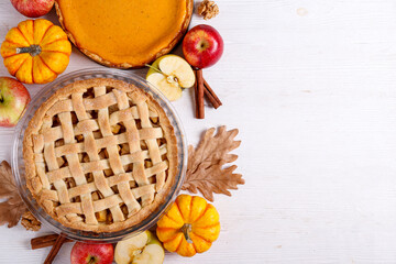 Two traditional American Thanks Giving pies with apples, mini pumpkins & cinnamon sticks. Homemade fruit tarts baked to golden crust. Close up, copy space, top view, background. © Evrymmnt