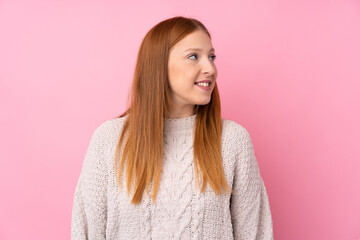 Fototapeta premium Young redhead woman over isolated pink background looking side