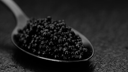 Fototapeta na wymiar black caviar imitation in black spoon close up