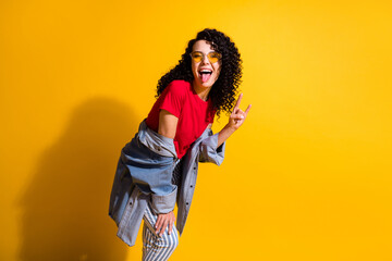 Photo of lovely young lady tongue-out show horns wear red t-shirt striped jeans jacket sunglass...