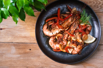 Delicious fried langoustines in sauce on a black plate, prepared in an Asian style. Fast and ready meal concept