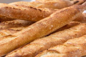 Freshly baked French baguettes lie on a light-colored surface. Rustic handicraft bread, handmade