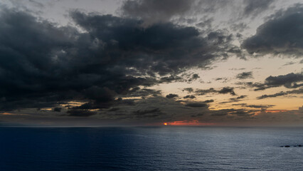 Atardecer melanc&oacute;lico con puesta de sol rojo y nubes negras