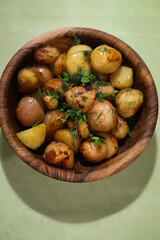 young fried potatoes in a wooden bowl seasoned with herbs