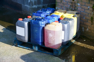 Oil barrel plastic canisters mixed colours at garage