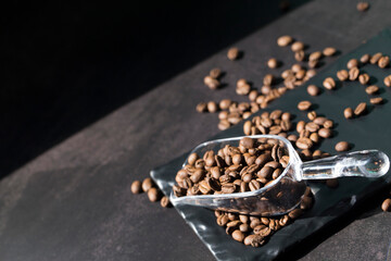 Obraz na płótnie Canvas Fresh coffee beans in plastic scoop on black background.