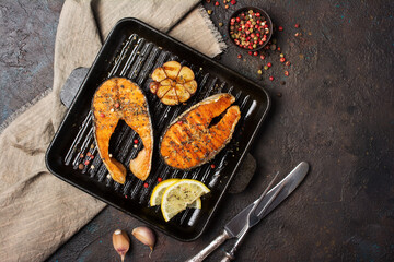 Spicy fried red fish salmon steak on grill pan with garlic and lemon