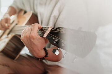 Selective focused man hands playing on guitar at home.