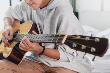 Student learning to play on acoustic guitar remotely at home