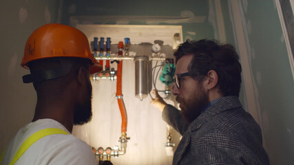Professional worker explaining owner work of independent heating system in boiler room