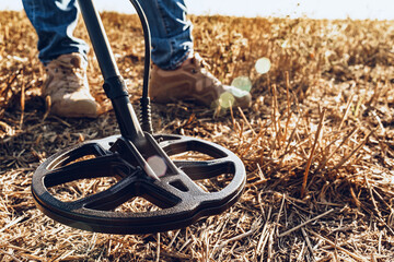 Man with metal detector equipment searching for metal goods in the field