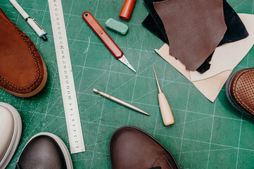 Ruler, awl, knife, paint and leather. Green background top view copy space