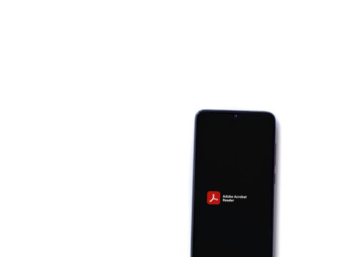 Lod, Israel - July 8, 2020: Adobe Acrobat Reader app launch screen with logo on the display of a black mobile smartphone isolated on white background. Top view flat lay with copy space.