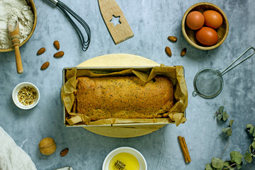 Homemade sugar-free cake with pumpkin, poppy seeds, raisins, almond flour and honey in a baking dish surrounded by ingredients, top view, flat lay, copy space. The concept of gluten free baking, keto 