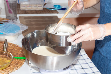 Using a sieve and a wooden spatula, the girl sifts the flour. Cooking process.